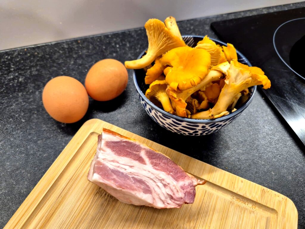 Świeże jajka, boczek i kurki przygotowane do zrobienia jajecznicy.